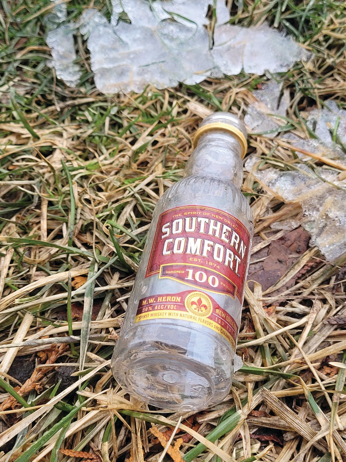NORTHEASTERN DISCOMFORT: A tiny bottle of Southern Comfort emerged from the ice and snow in the grass along Atwood Avenue in Johnston, likely tossed from a car window.